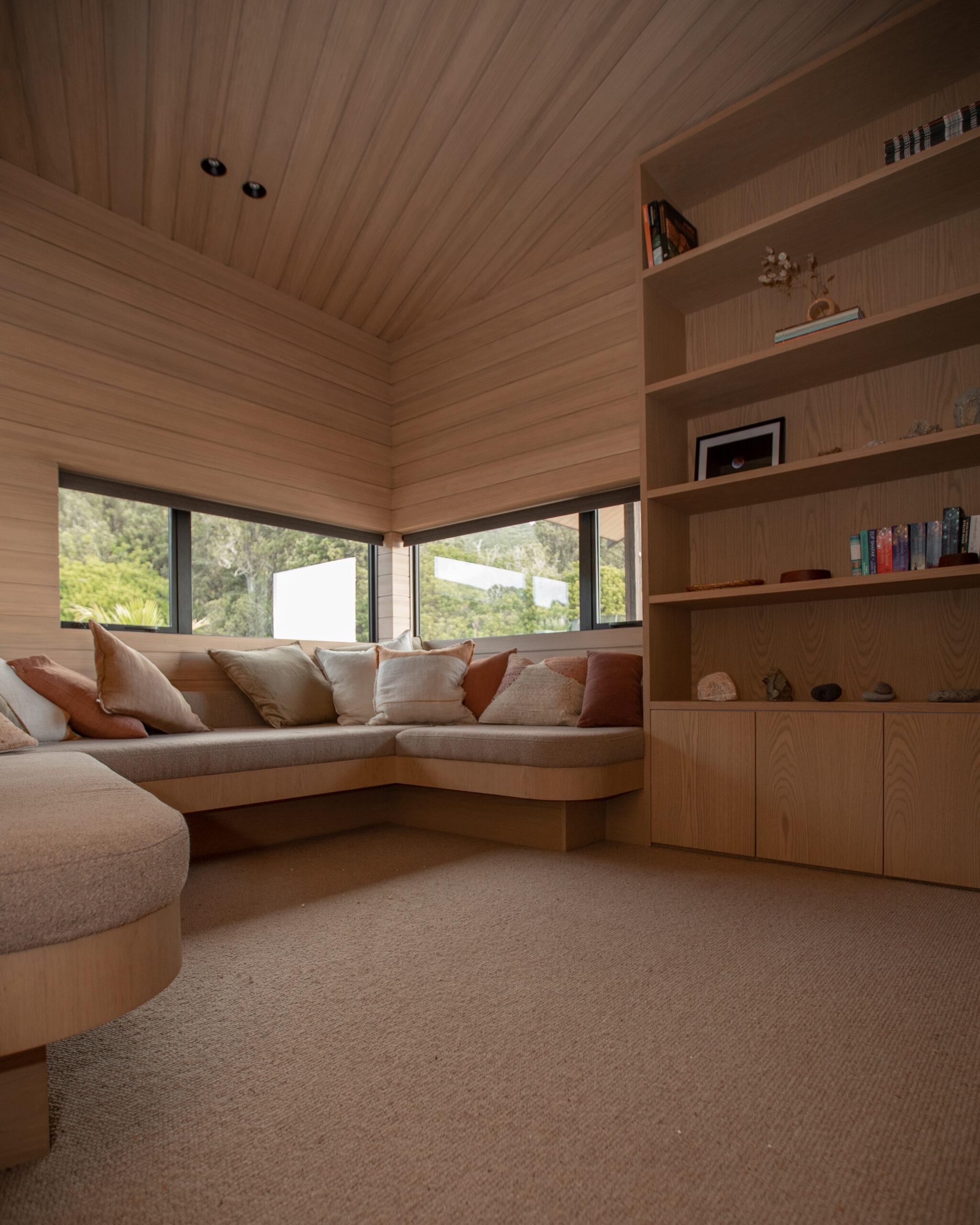Curved edge couch blending into the roof height shelf in this clients living area